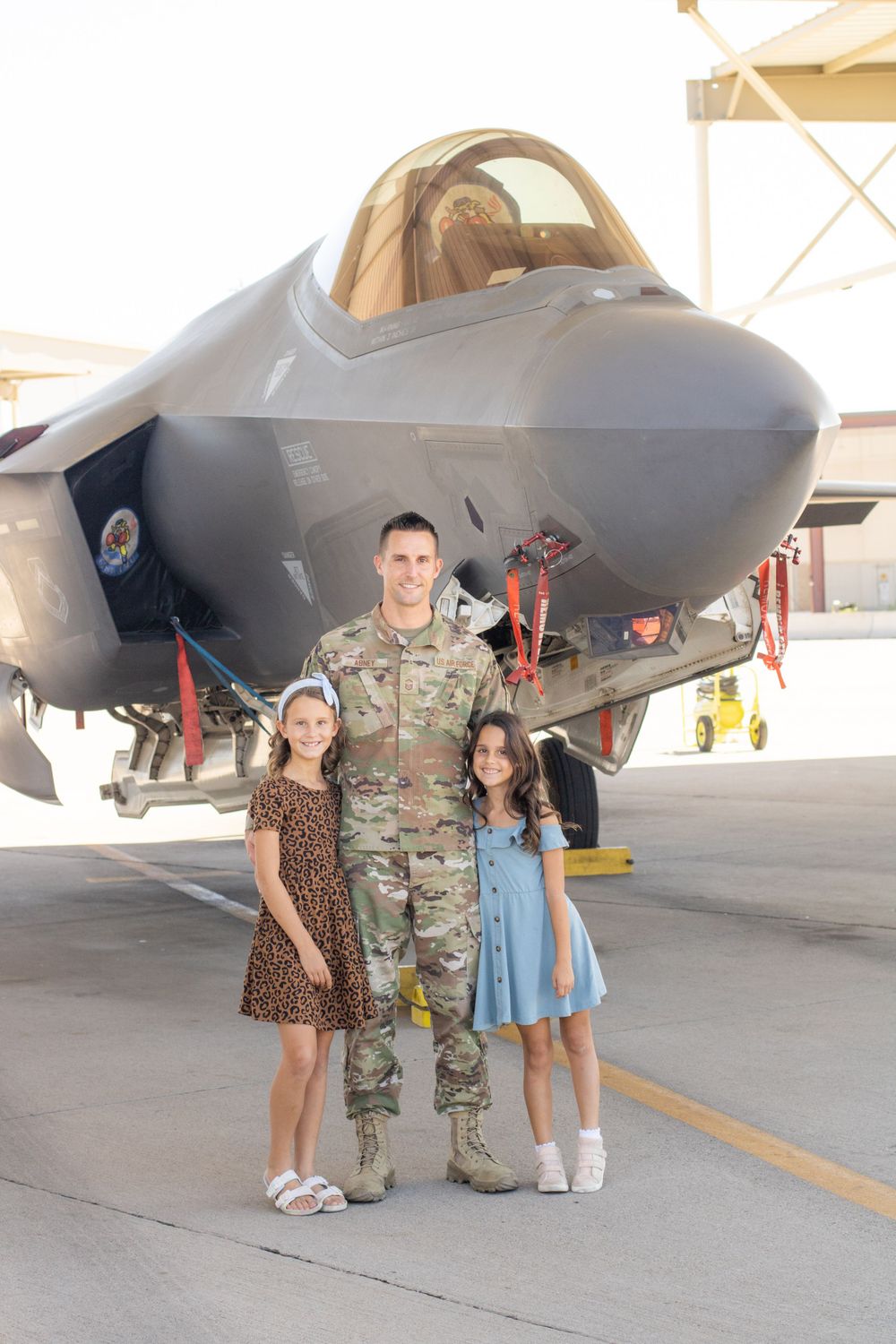 Dad celebrating military retirement with daughters. Military aircraft.