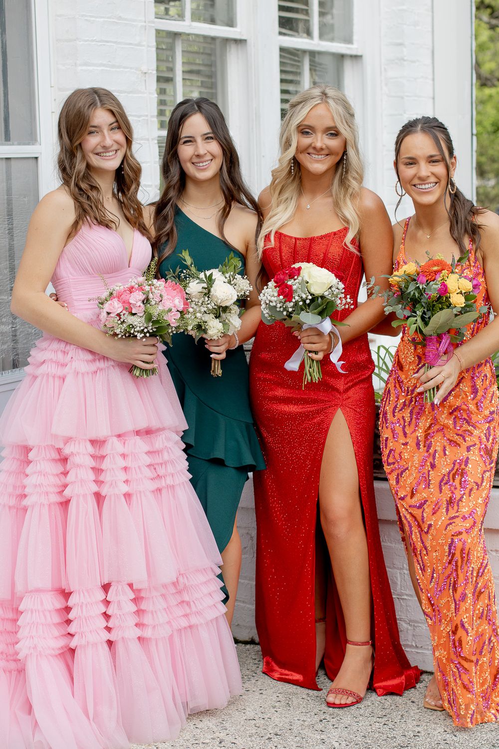 Girlfriends going to prom holding floral bouquets. Girls in beautiful dresses. Girls wearing formal gowns. Best friends.
