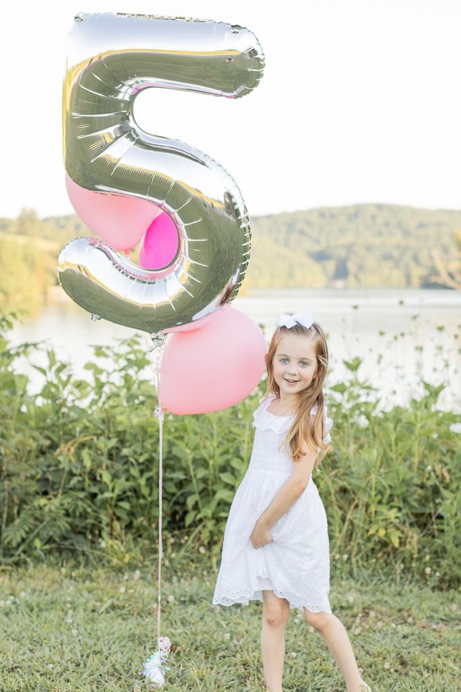 5th birthday party. Little girl with five balloon. Turning five.