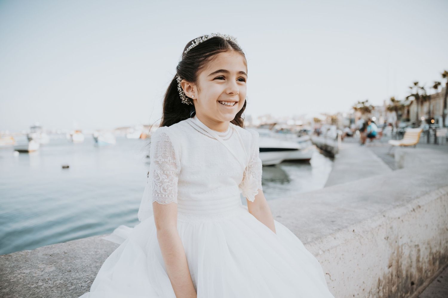 Girl in white dress smiling during sunset beach photoshoot.