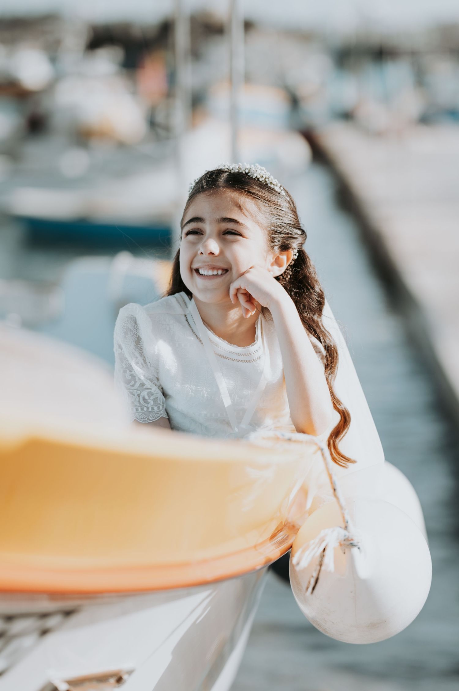 A bride in white dress laughing and posing playfully against a blurred marina background.