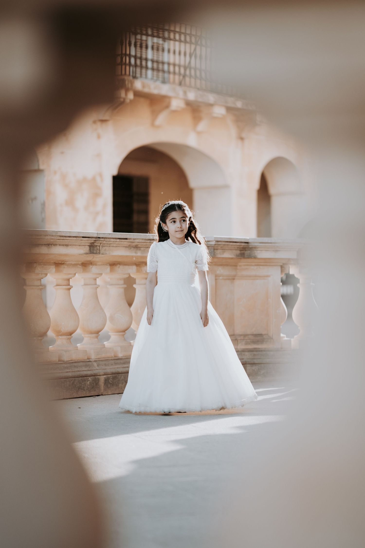 Dreamy portrait in white dress among stone architecture.