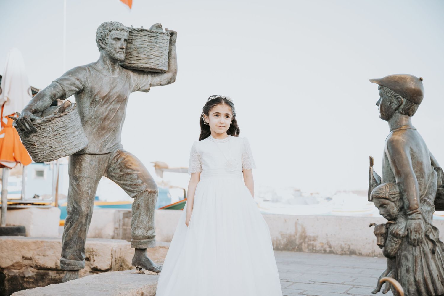 White dress flowing against a backdrop of classical stone statues and palm trees.