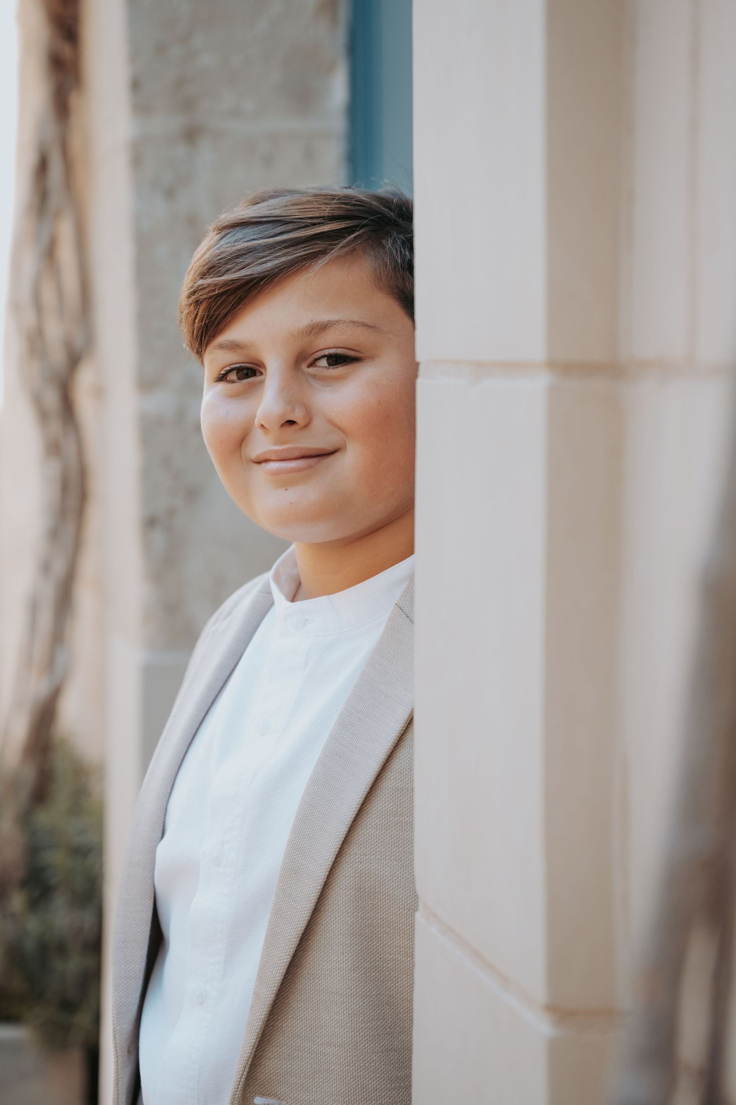 Close-up portrait showing a gentle smile against a backdrop of white architectural columns.