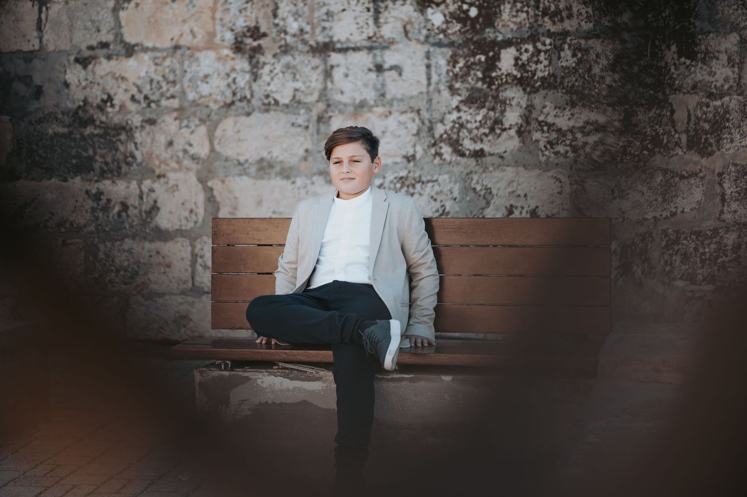 Moody portrait against a textured brick wall showing someone in formal attire.