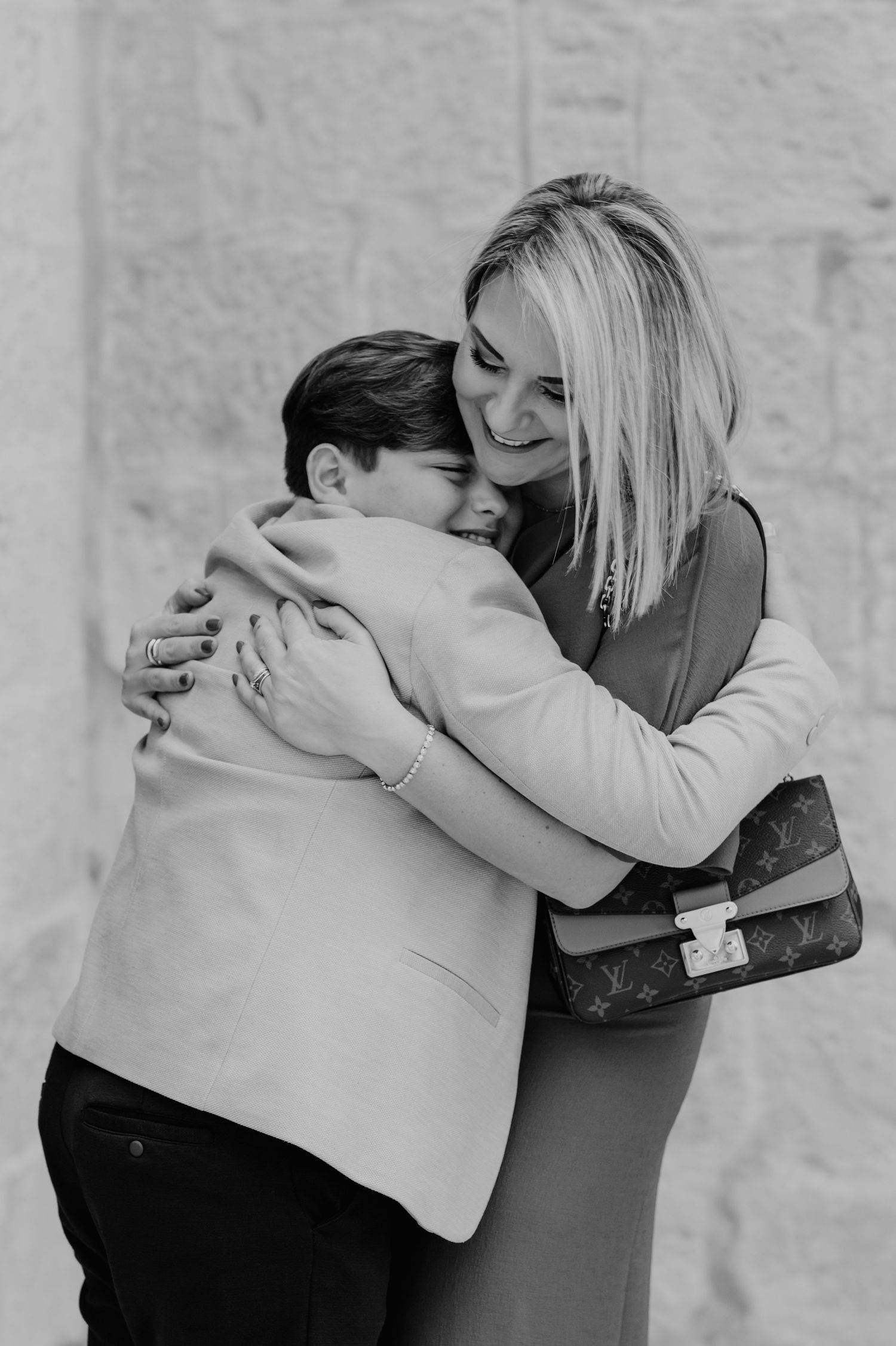 Two people share an emotional embrace in a heartfelt moment against a light background.