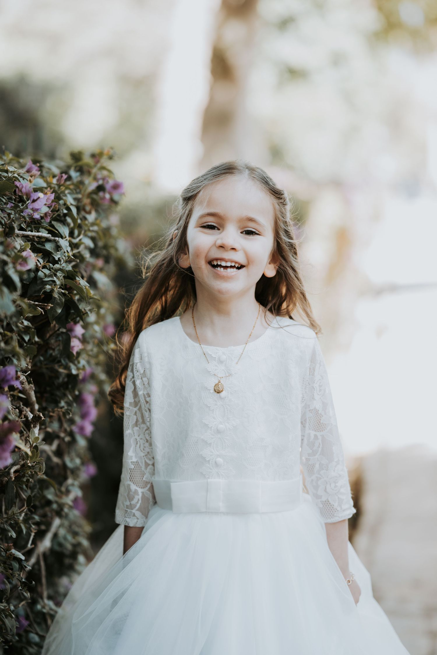 Natural light portrait in garden setting with purple flowers and white dress.