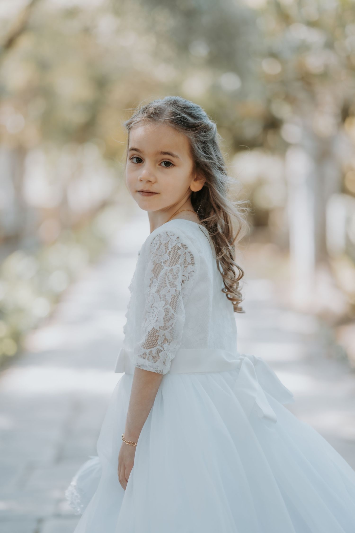Delicate lace sleeve white dress captured in soft, dreamy outdoor lighting.