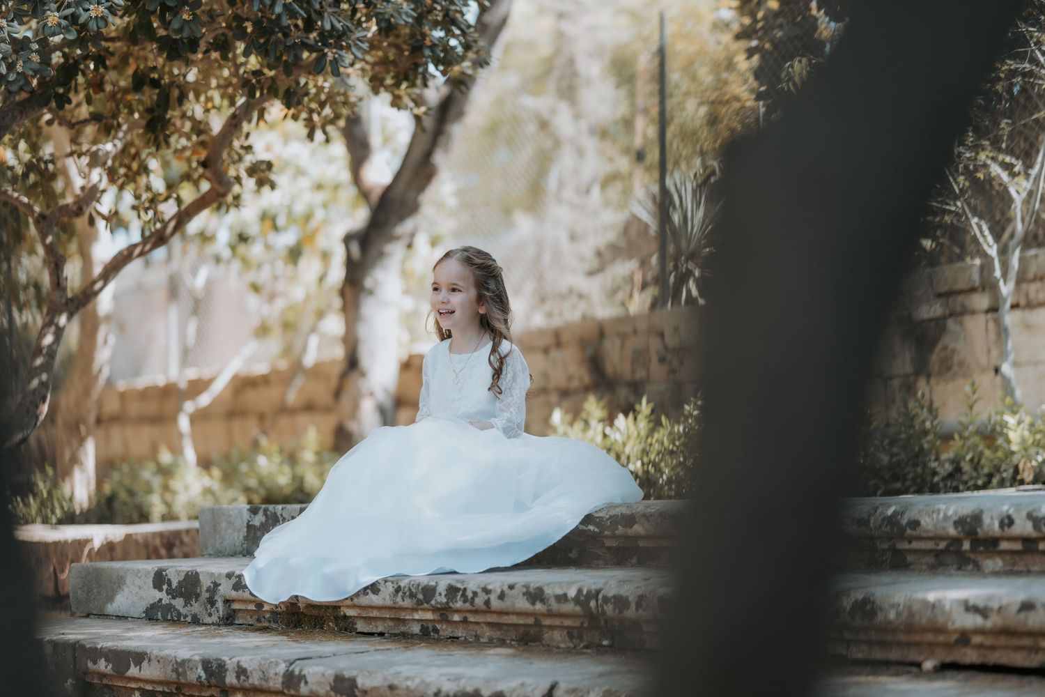Artistic photo composition with white dress contrasting against stone wall and natural foliage.