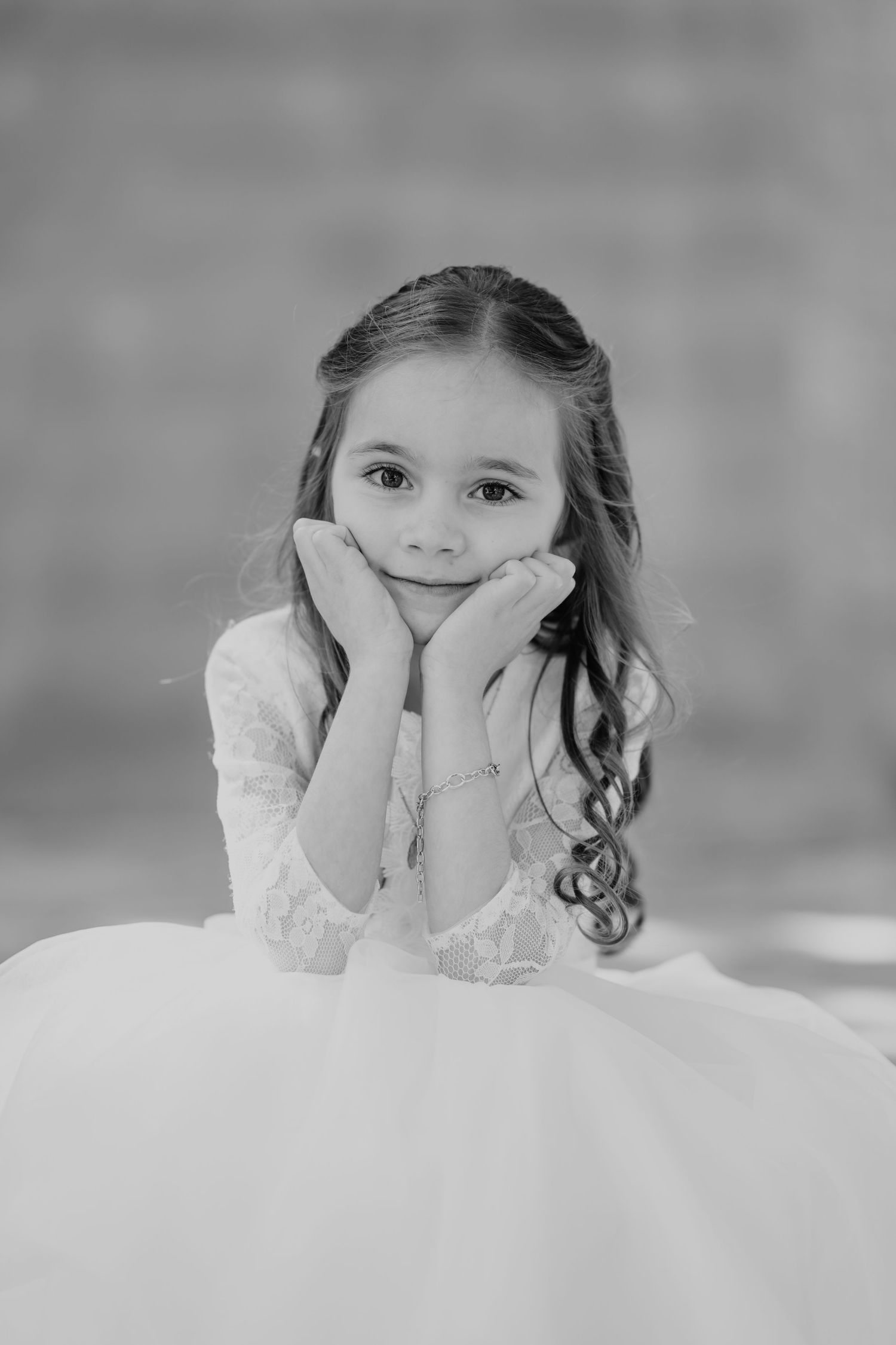 Black and white portrait series showing a child in white lace dress resting head on hands with dreamy expressions.