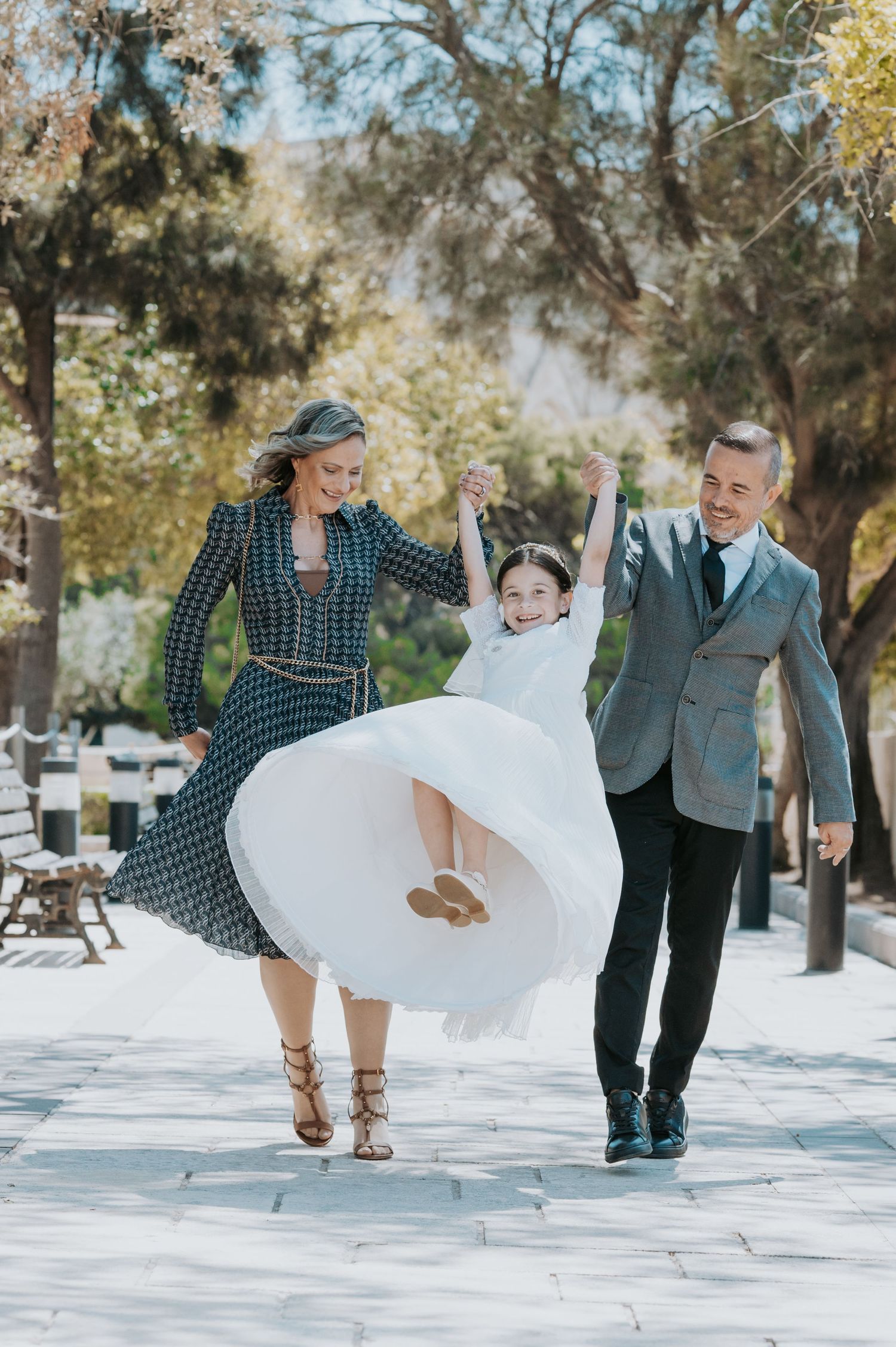 A playful series of photos showing a couple in formal wear dancing and twirling on a tree-lined path.