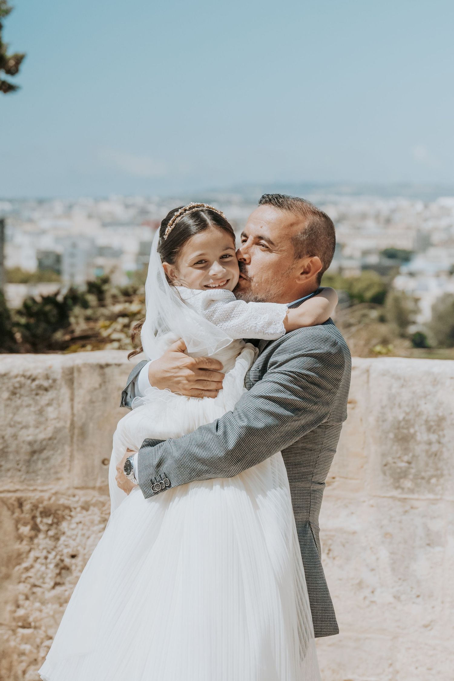 Emotional embraces between two people in formal wear against a scenic hilltop backdrop.