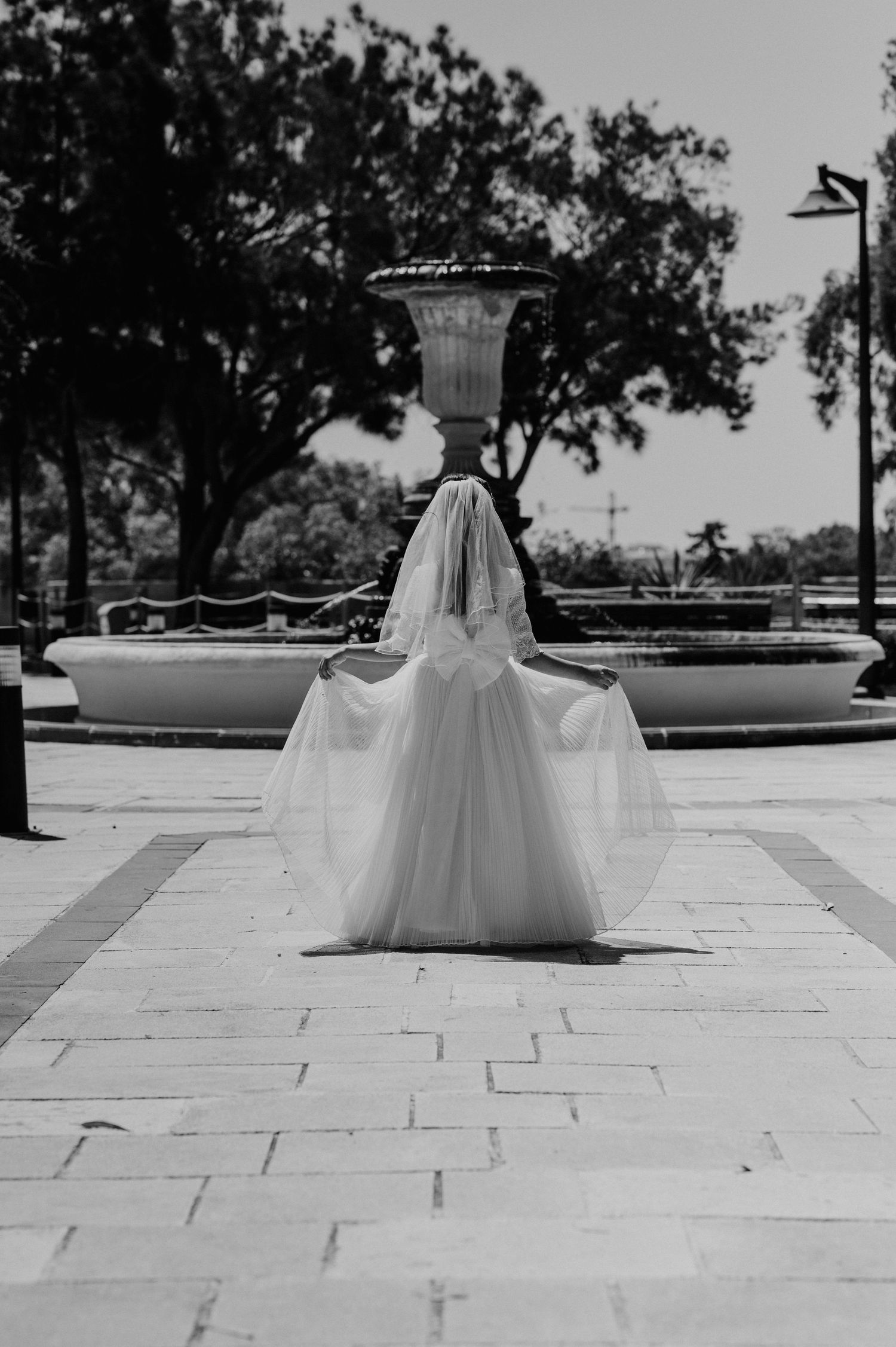 Black and white photos of a person in a flowing white dress on a stone courtyard.