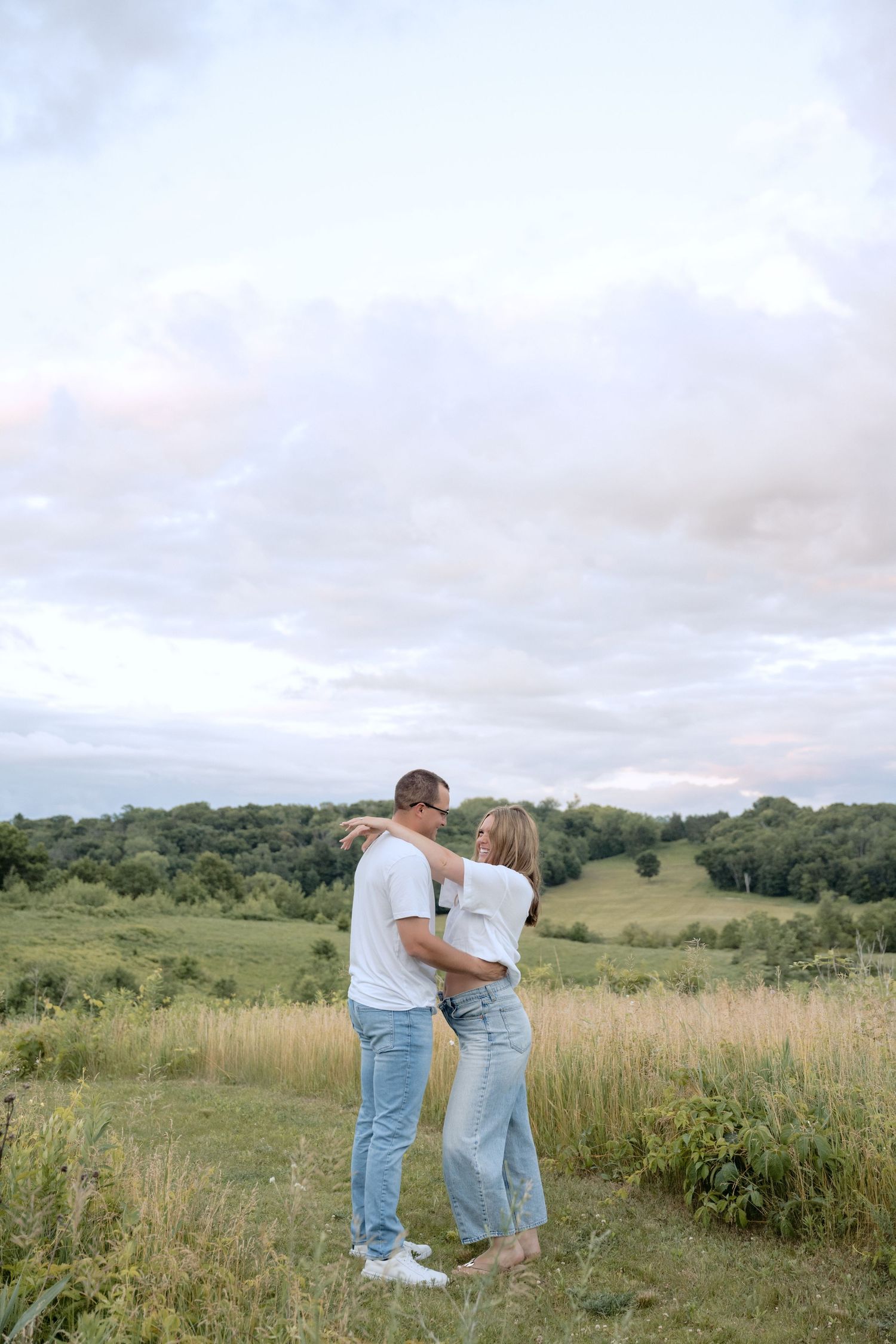 couple stares lovingly at each other while celebrating pregnancy announcement for rolling hills field portraits in hudson WI with jagger