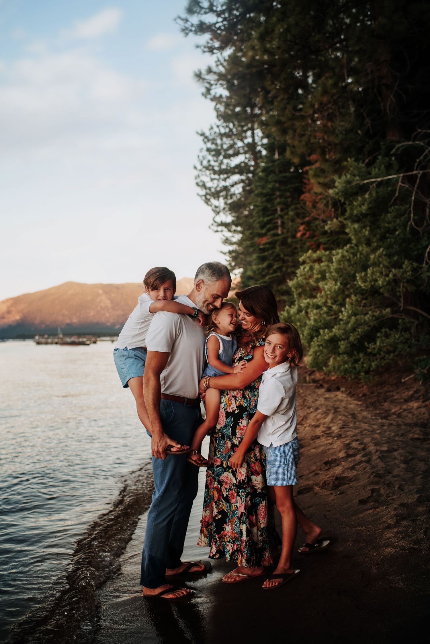 Family hugging at Lake Tahoe, sunset glow on faces. Documentary-style joy.