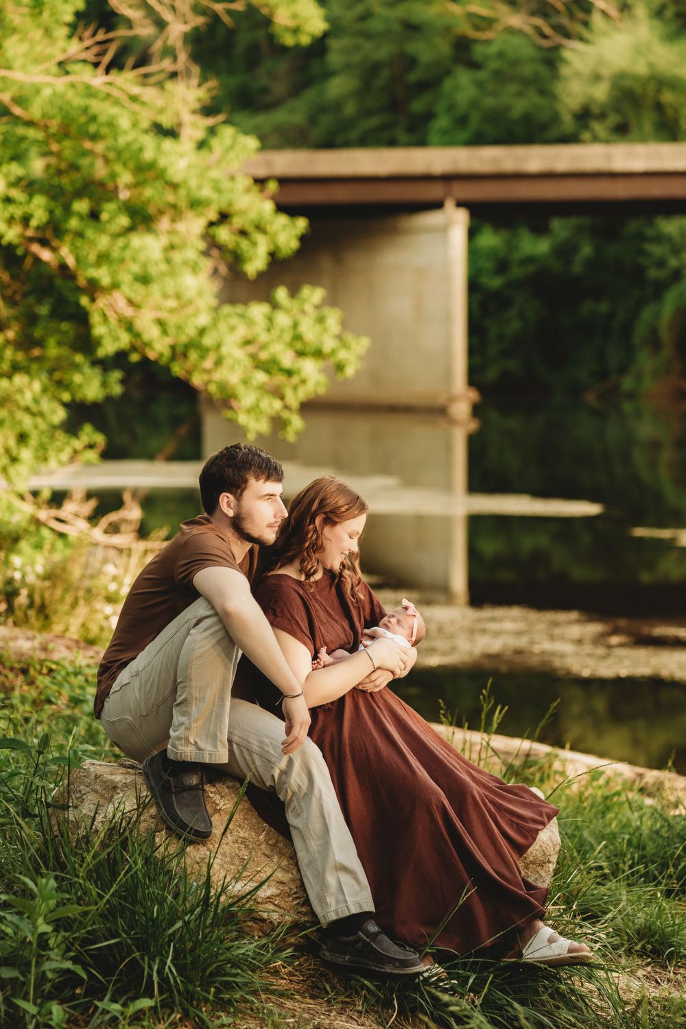 A couple relaxes together on grassy riverbank in vintage-styled clothing.