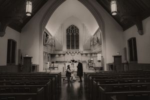 Black and white photo of a marriage proposal inside a historic church with vaulted ceilings and wooden pews.