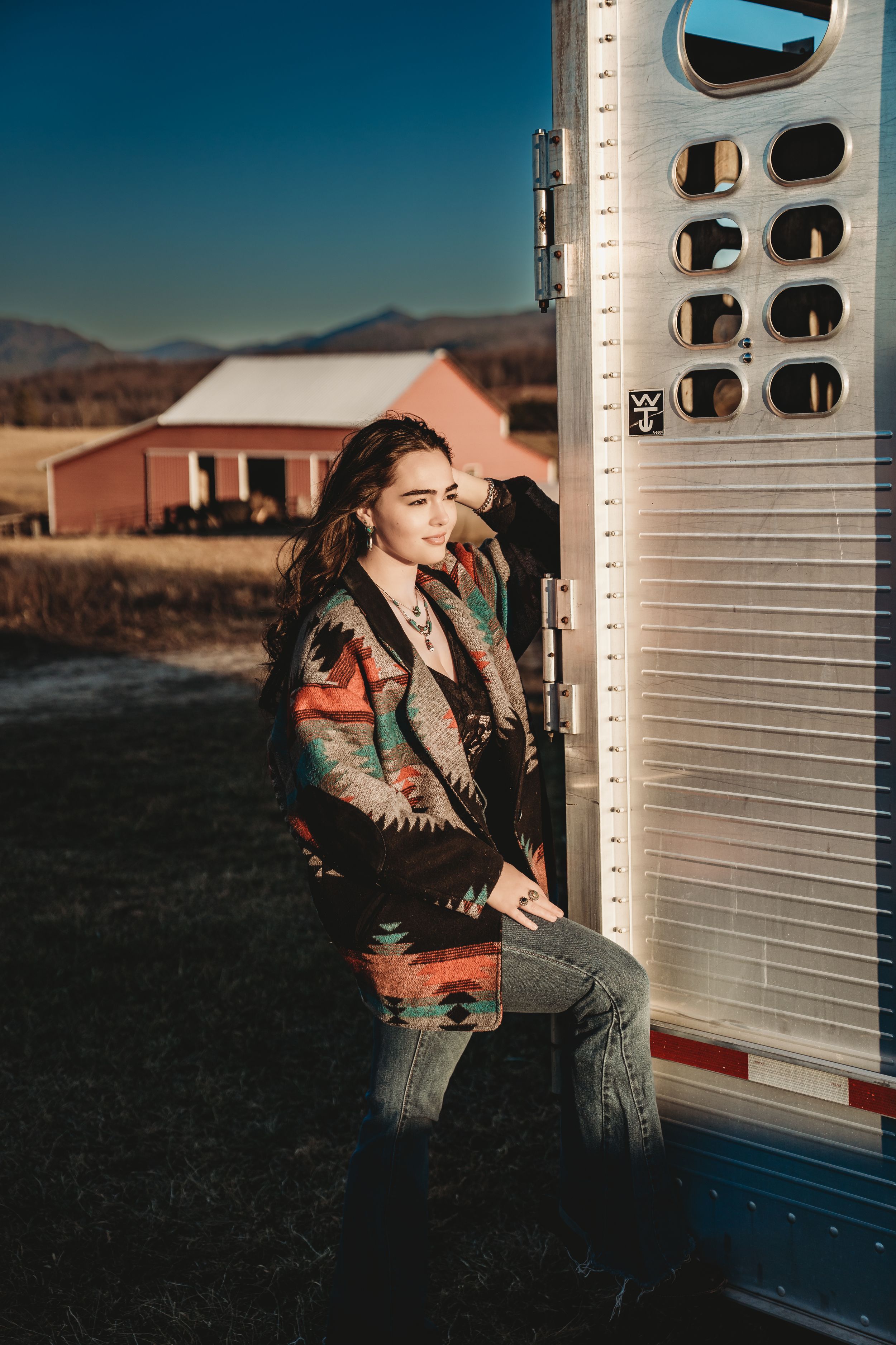 Artistic portrait series against vintage camper with dramatic sunset lighting and desert mountain backdrop in the distance.