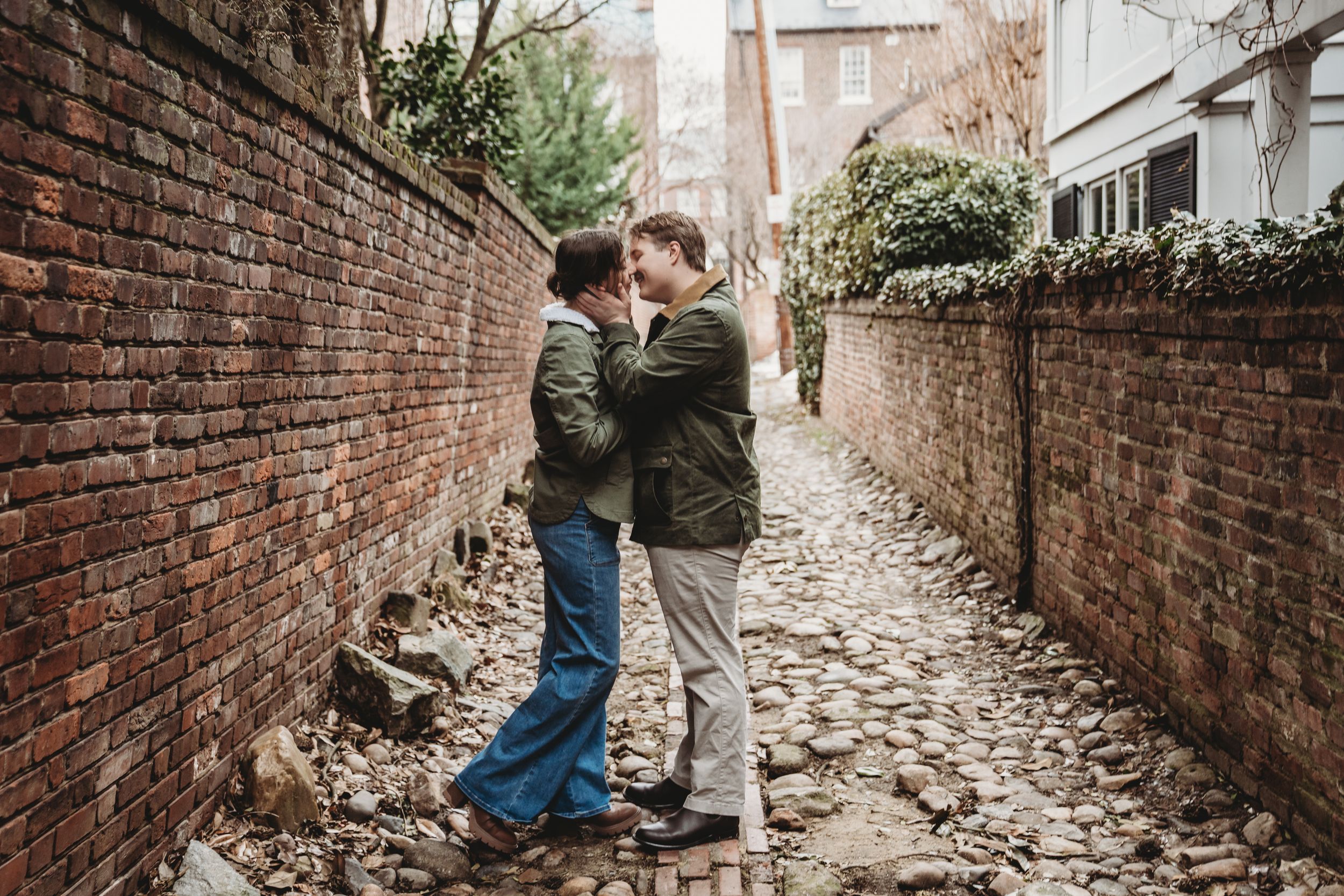 A couple shares a romantic moment in a narrow brick alleyway during their engagement photo session.