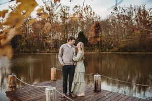 A serene lakeside dock scene with fall trees reflecting in calm waters.