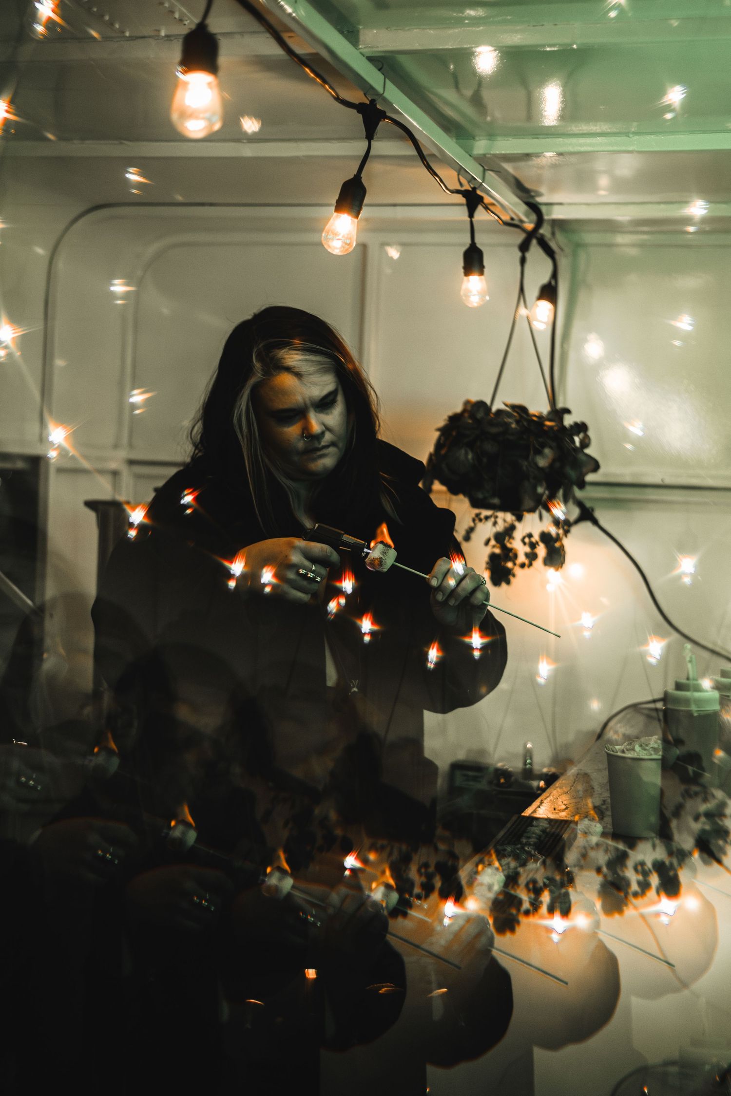 Figure arranging string lights in dark bar setting with dramatic lighting.
