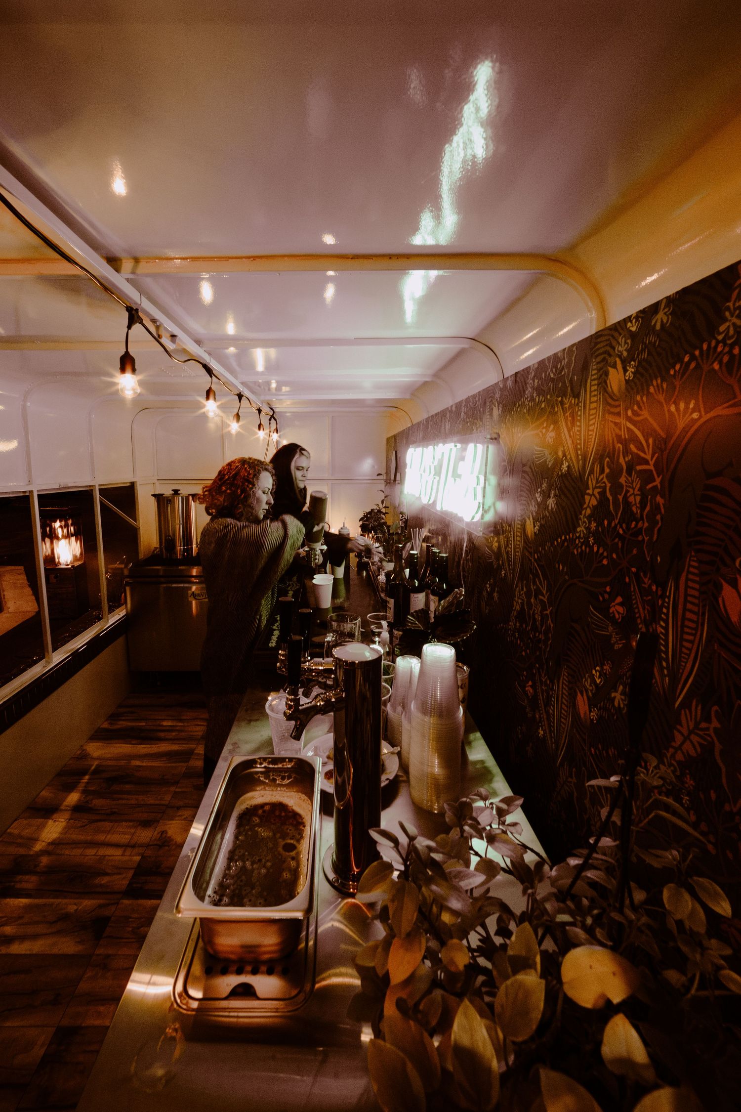 Moody interior shot of cafe bar with string lights and tropical wall decor.