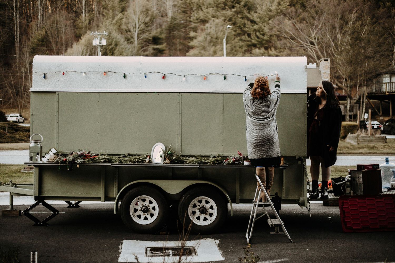 People setting up a mobile food trailer outdoors in winter conditions.
