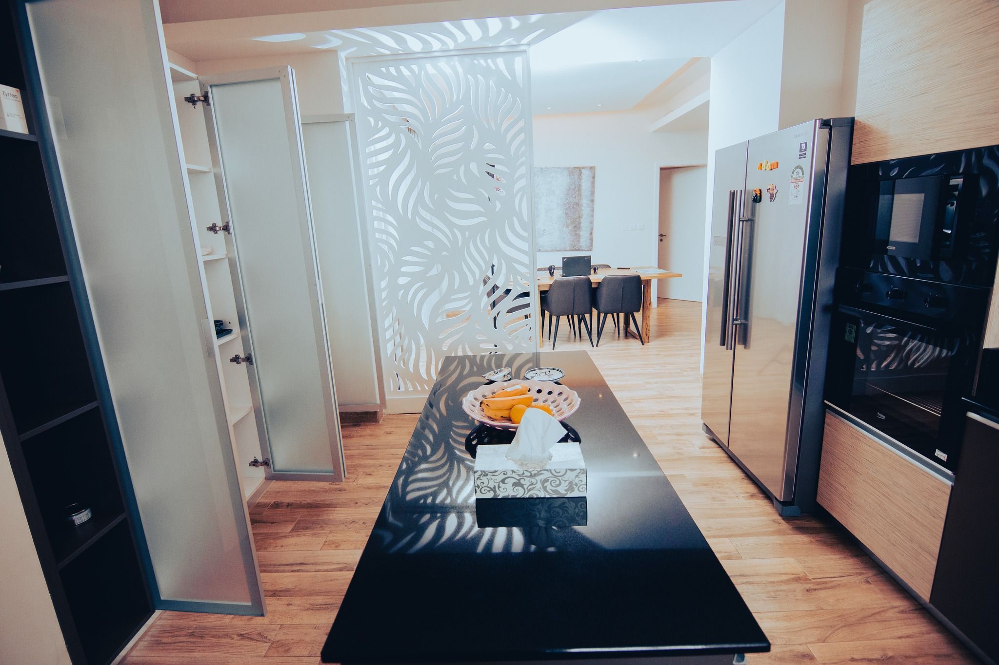 Sleek kitchen and dining area with black appliances and modern lighting fixtures.