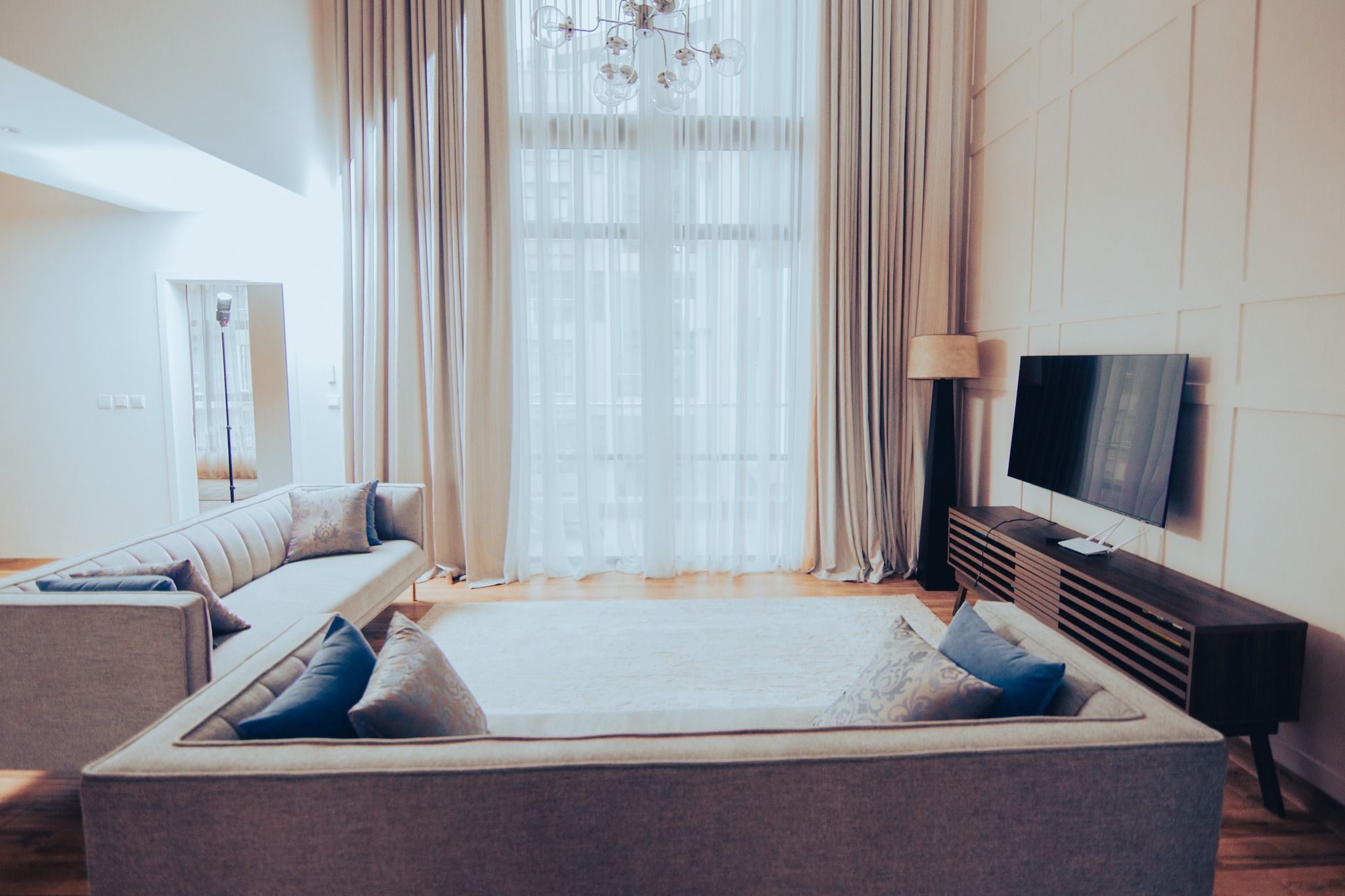 Elegant bedroom with sheer curtains, plush bedding, and mounted TV.