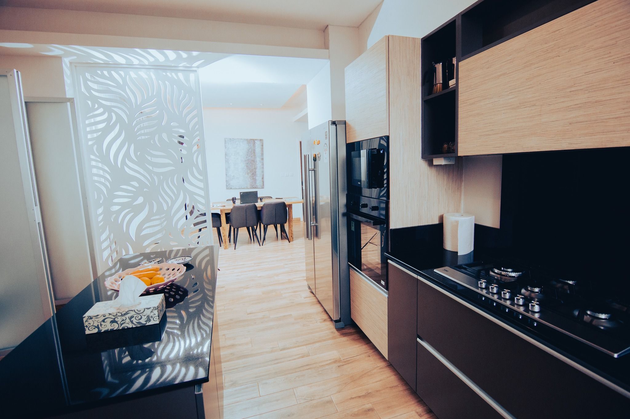 Open concept kitchen with wooden floors and black appliances.