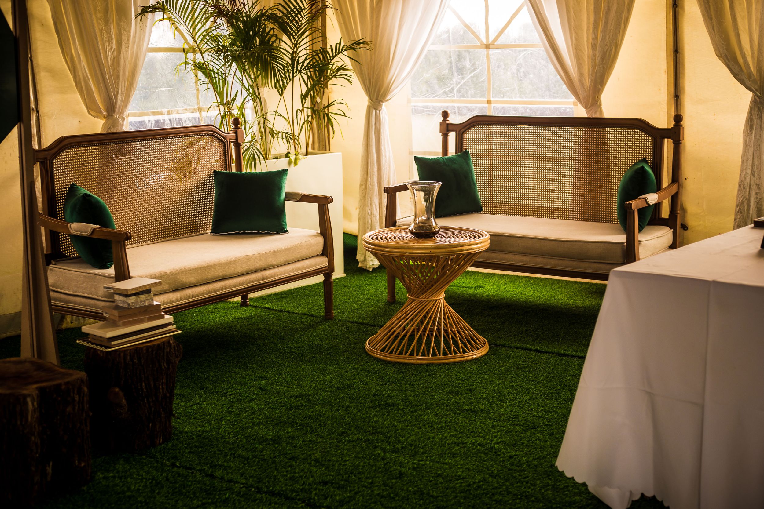 Elegant event space with white curtains, artificial grass flooring and ambient lighting.