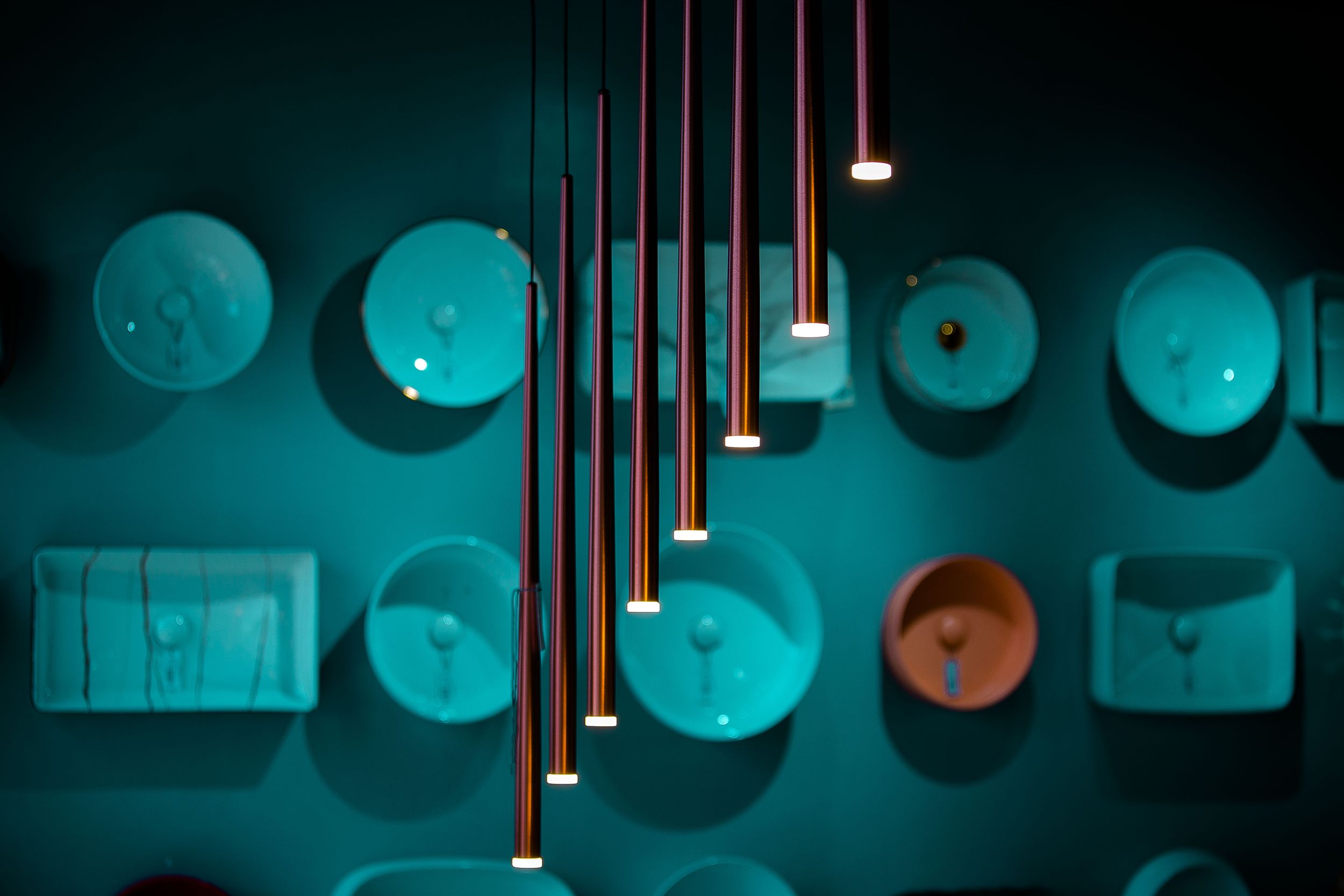 Turquoise-tinted decorative wall with hanging pendant lights and circular wall art.