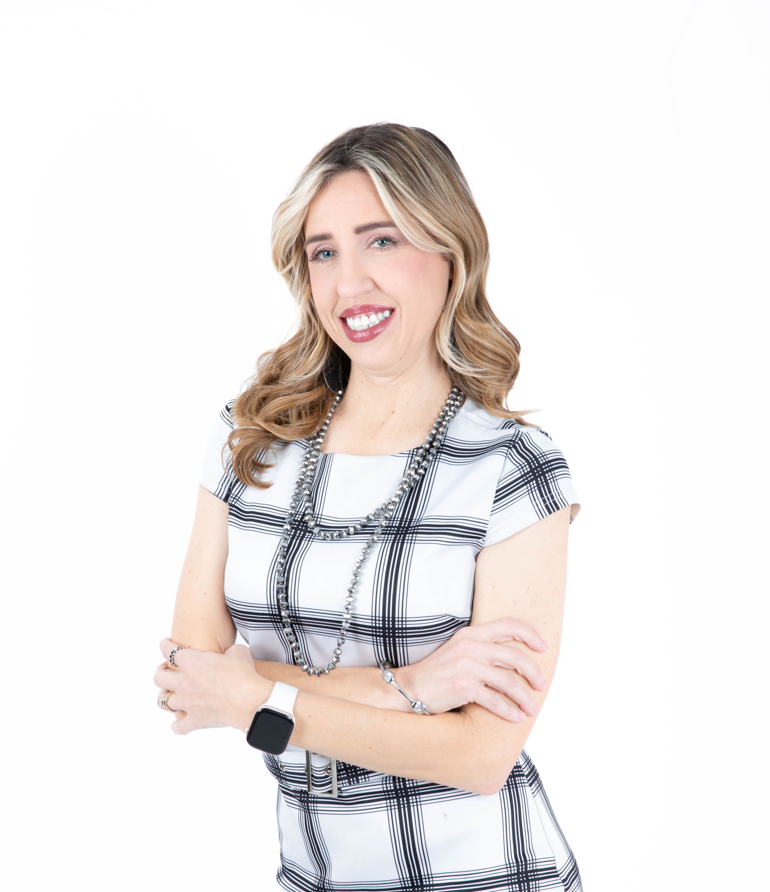 Professional portrait of someone wearing a black and white plaid short sleeve top with arms crossed and a warm smile.