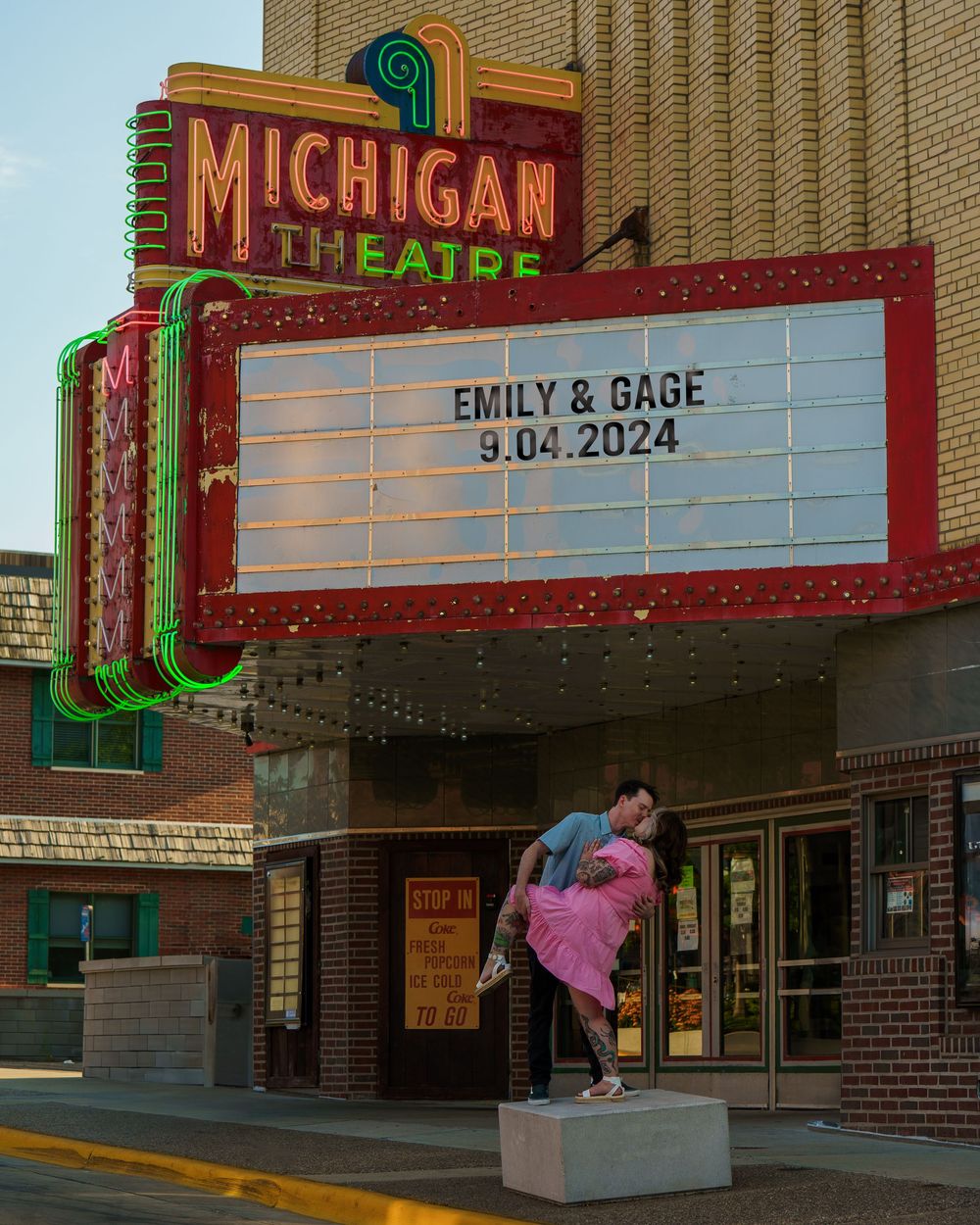A couple poses dramatically beneath the vintage Michigan Theatre marquee displaying their names and date 9.04.2024.