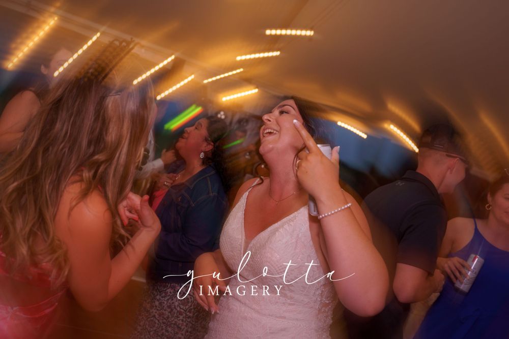 Couples dancing and kissing on a dimly lit dance floor at a wedding reception with warm golden lighting.