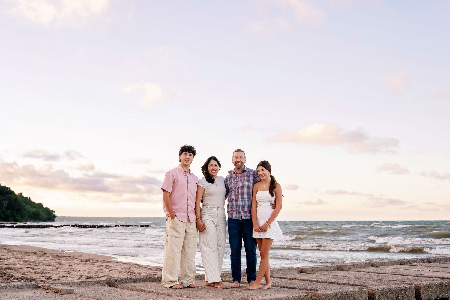 Photo of a family standing on the beach at sunset taken by Milwaukee family photographer Rachel Dickman.