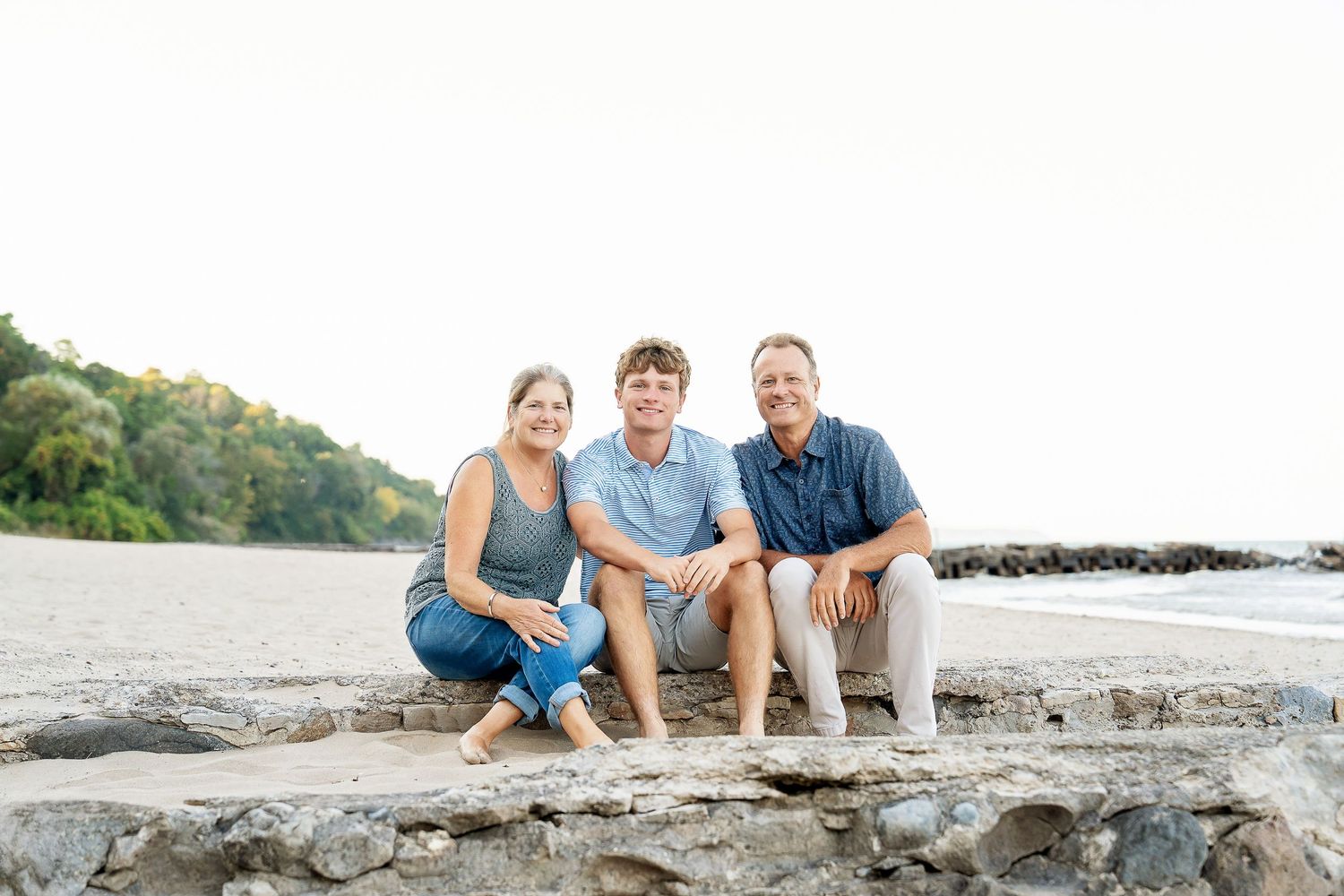 A family of three sitting at the beach together at sunset taken by Milwaukee family photographer Rachel Dickman.