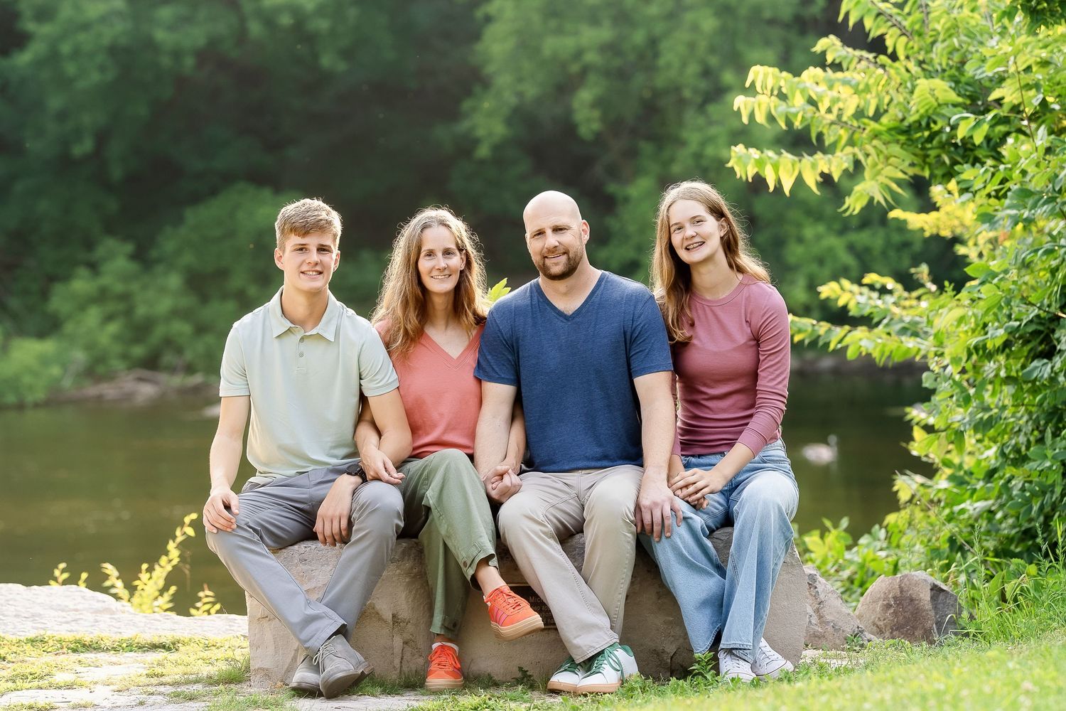 Photo of a family sitting on a stone bench in front of a river taken by Milwaukee family photographer Rachel Dickman.