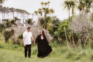 A couple takes a romantic stroll through lush greenery with palm trees and native plants in a natural outdoor setting.