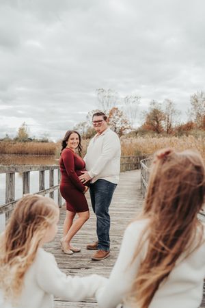 A couple shares a playful moment on a wooden boardwalk during an autumn photo session.