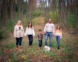 Autumn family portrait in woods with dog among fallen leaves.