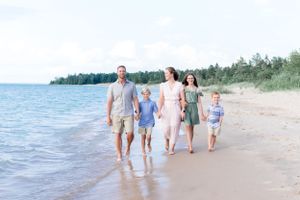 A family walks together along a pristine beach shoreline on a bright summer day.