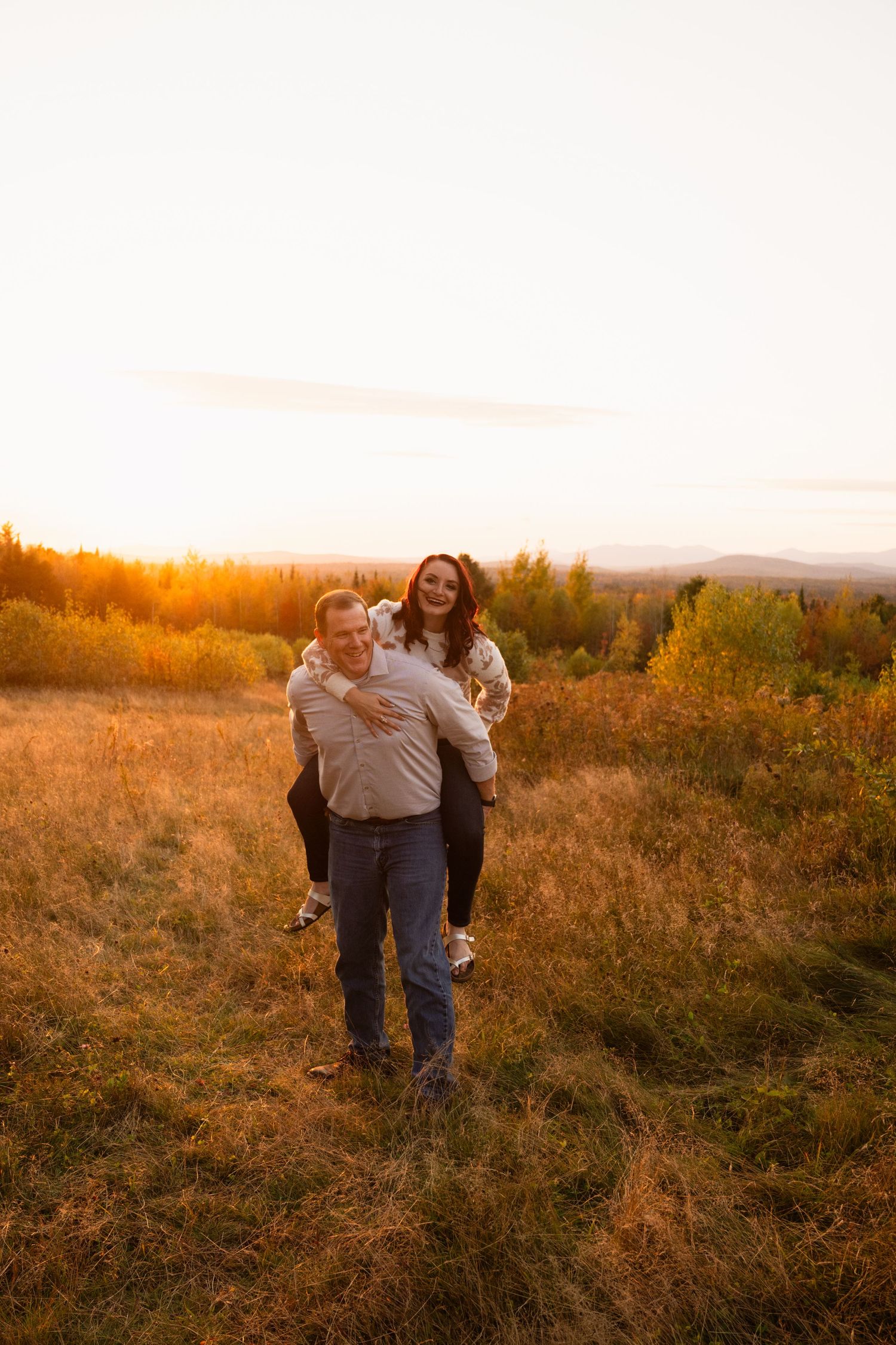 A couple sharing playful moments in a golden field during sunset.