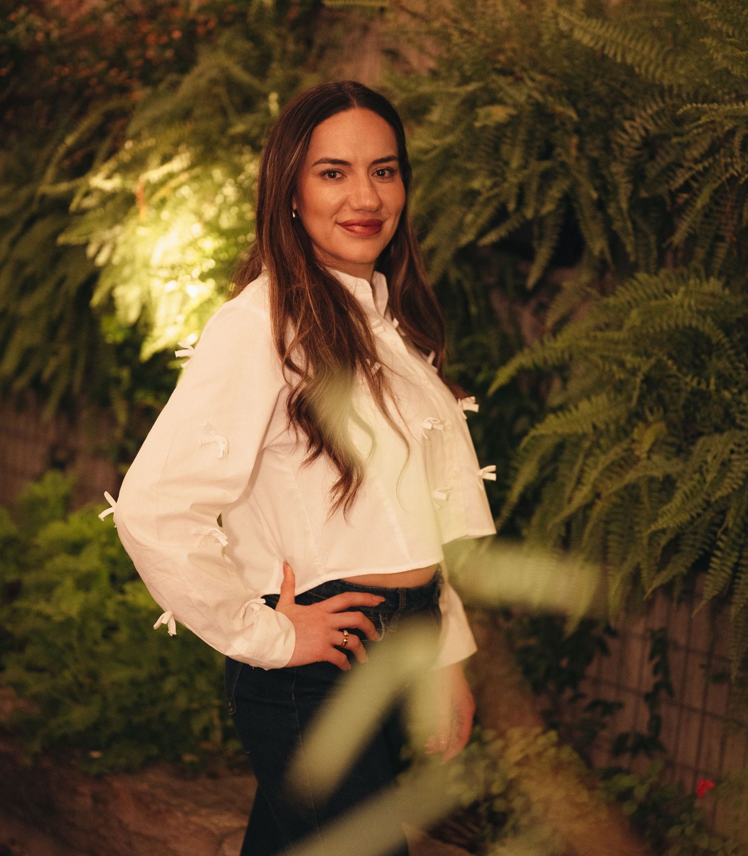 Portrait series of woman in white blouse against lush garden foliage at night.