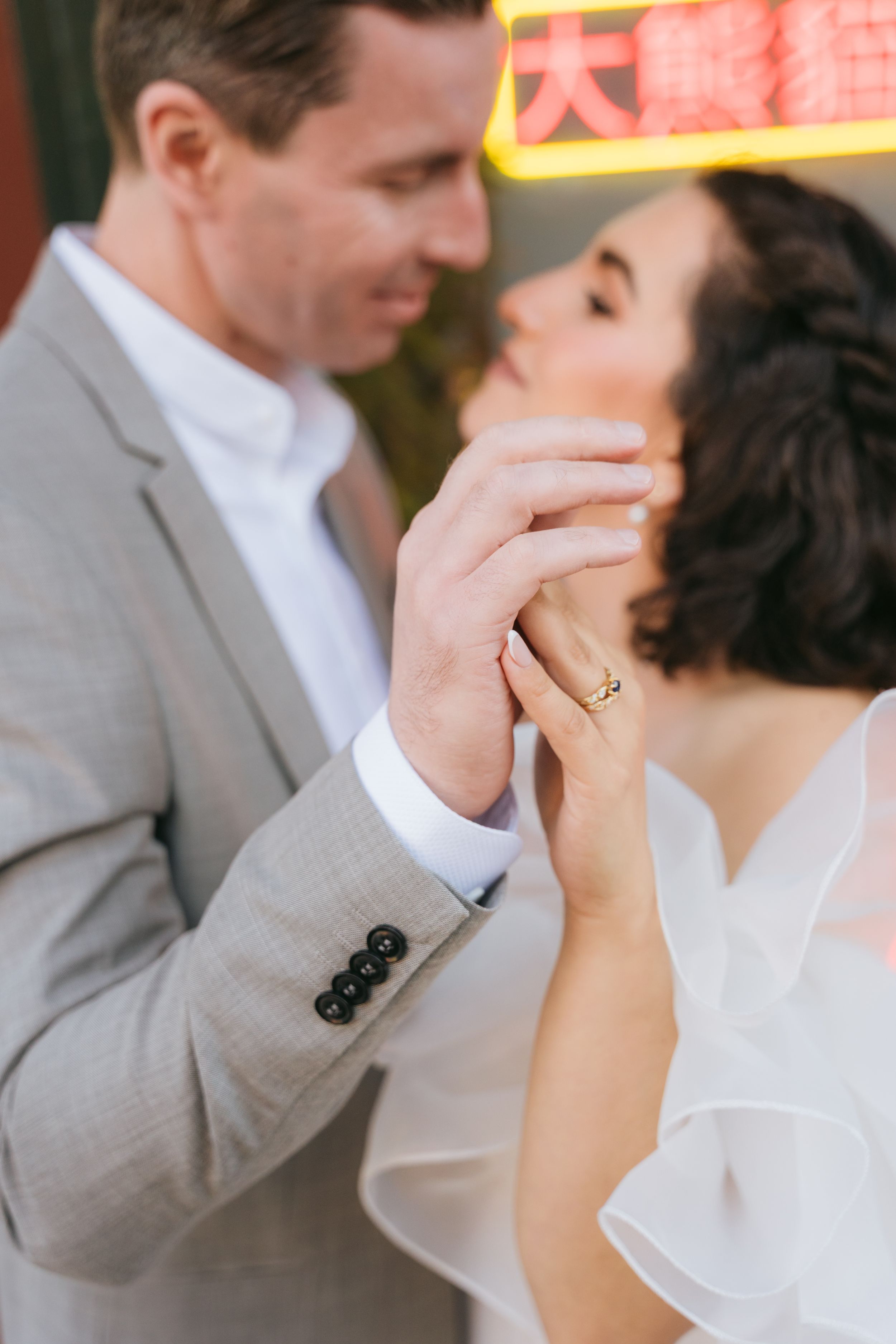 A romantic moment captured between a couple in formal attire against neon lights.