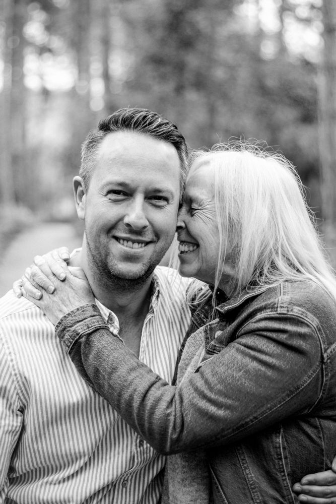 Black and white photo series showing a romantic couple embracing and laughing together in a forest setting.
