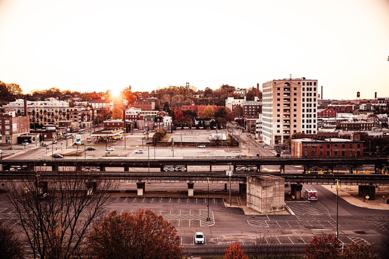 Orange bridge spans across calm river with Richmond skyline reflecting in water at dusk.
