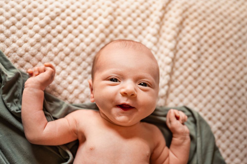 A collection of six close-up photographs showing a baby in various poses on a textured background.
