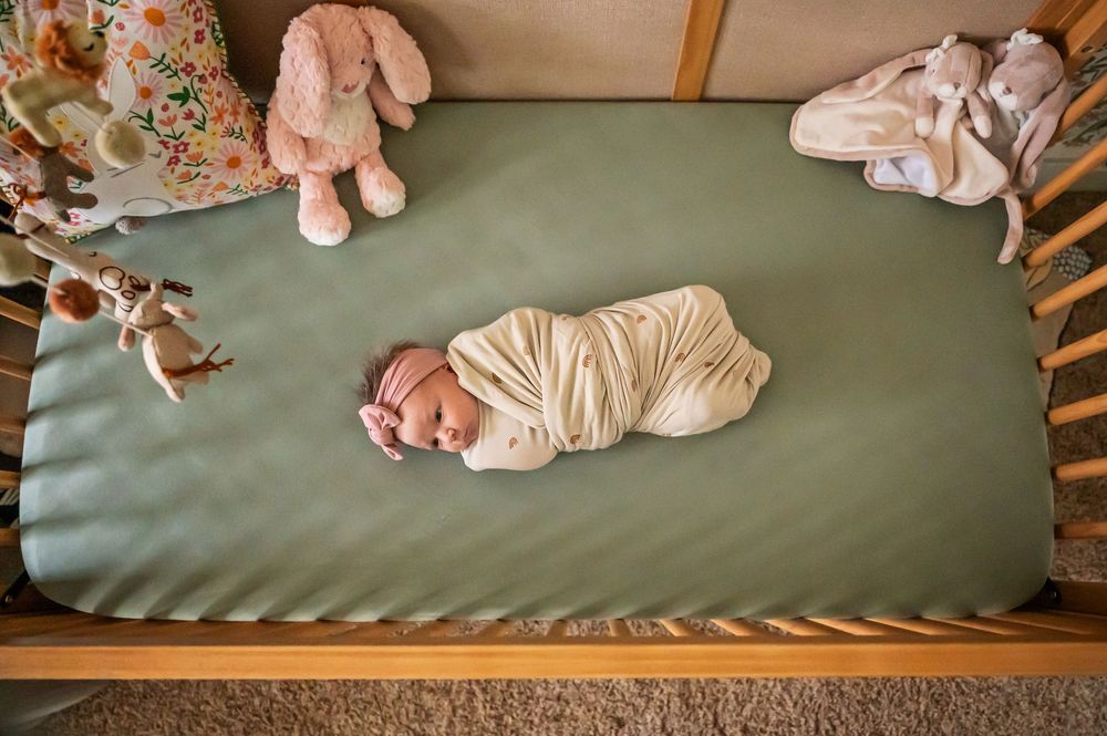 Seven sequential photos show a baby in pink clothing rolling and moving across a green couch cushion.
