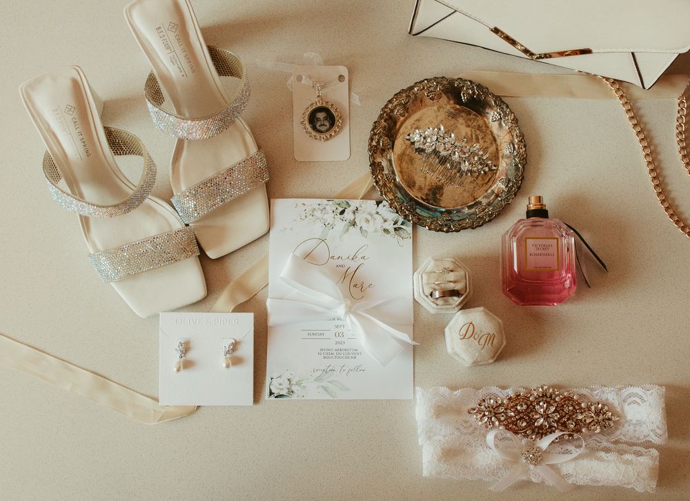 Elegant wedding flat lay featuring bridal shoes, rings, invitations, and perfume.